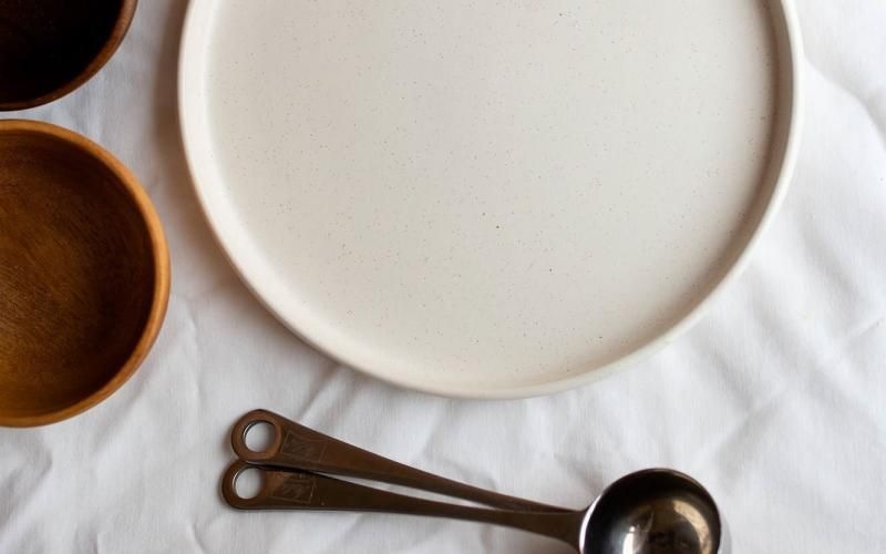 bowls, a plate and measuring spoons arranged neatly on cloth